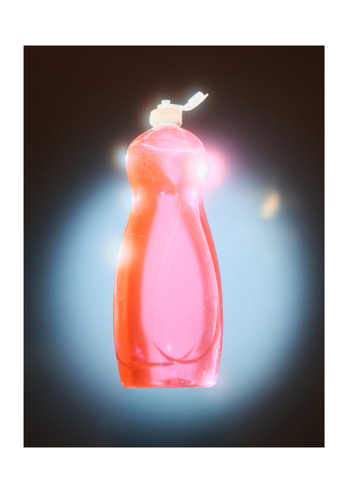 A translucent pink plastic bottle with a white flip-top cap, centered against a dark background with a bright blue glow and light flare effects.