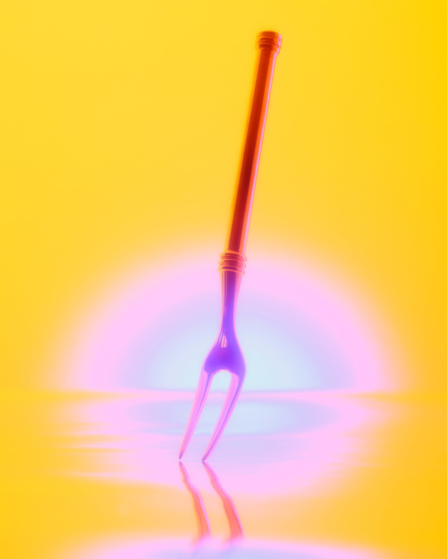 A neon-colored two-pronged fork standing upright on a reflective yellow surface against a glowing yellow background with pink and blue light effects.