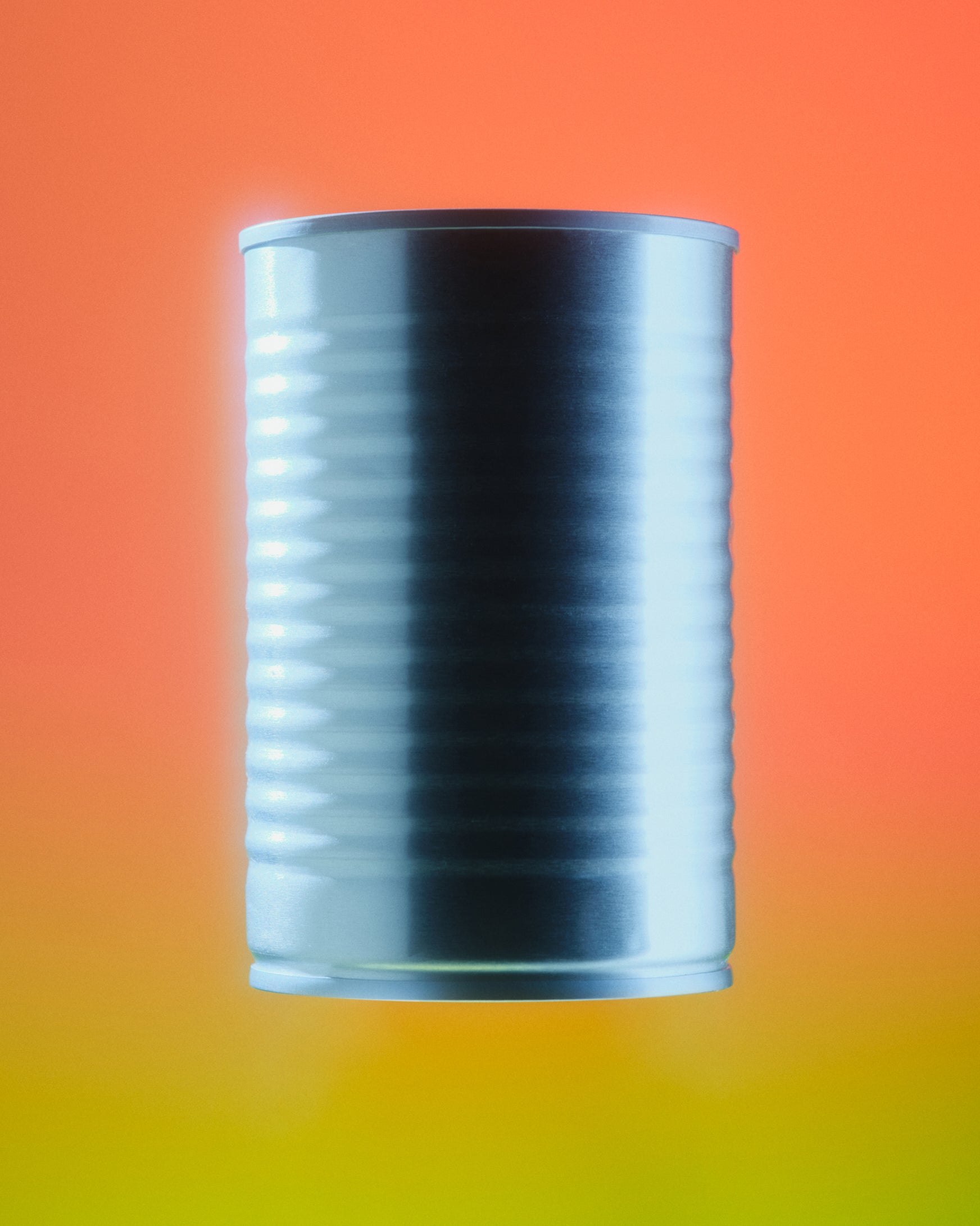 A metallic silver cylindrical can centered on a smooth gradient background that transitions from orange at the top to yellow at the bottom.